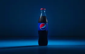 Pepsi glass bottle lit against a dark blue background