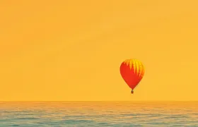 Hot air balloon drifting over the open ocean at sunset