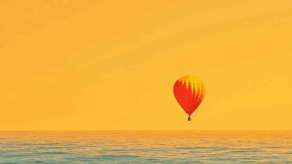 Hot air balloon drifting over the open ocean at sunset
