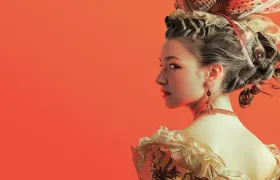 Woman in tall powdered rococo hairstyle with feathers and ruffled gown