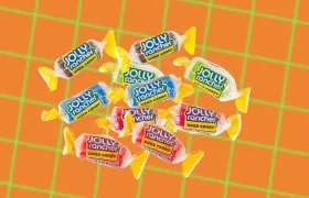 Assorted Jolly Rancher hard candies in wrappers on an orange background
