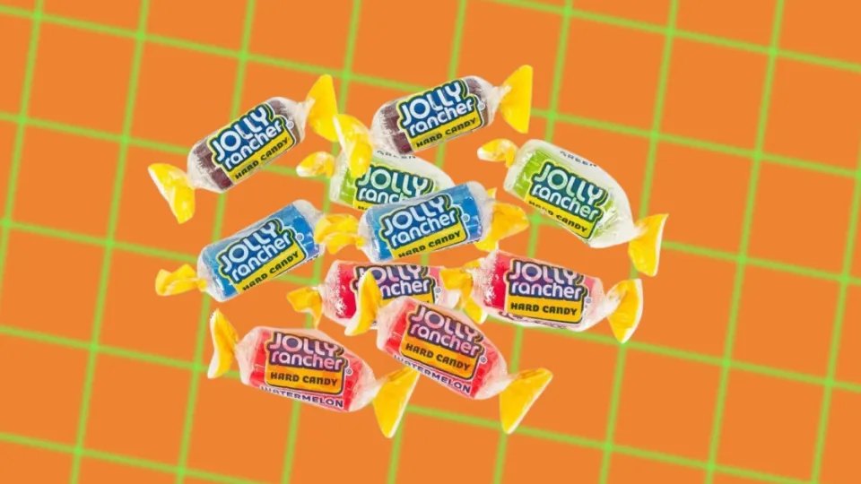 Assorted Jolly Rancher hard candies in wrappers on an orange background
