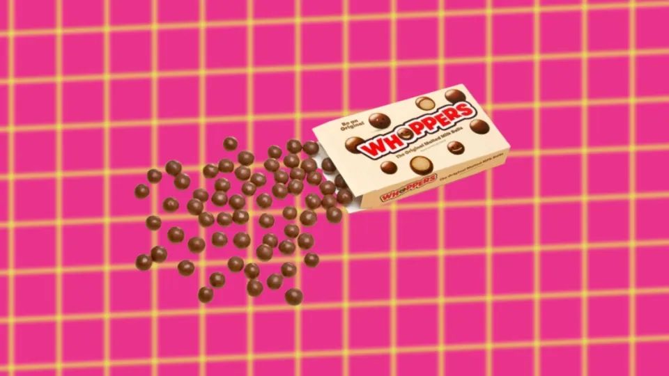 Whoppers box spilling malted milk balls on pink grid background