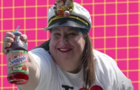 Wendy Kaufman holding a Snapple Apple bottle in a fruit-topped captain hat