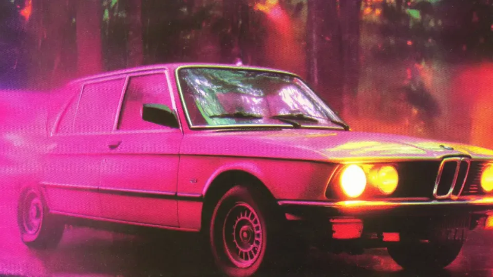 Vintage BMW 5 Series sedan with glowing headlights in neon pink