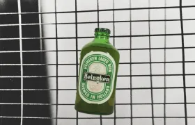 Green Heineken lager beer bottle against a black-and-white tiled wall