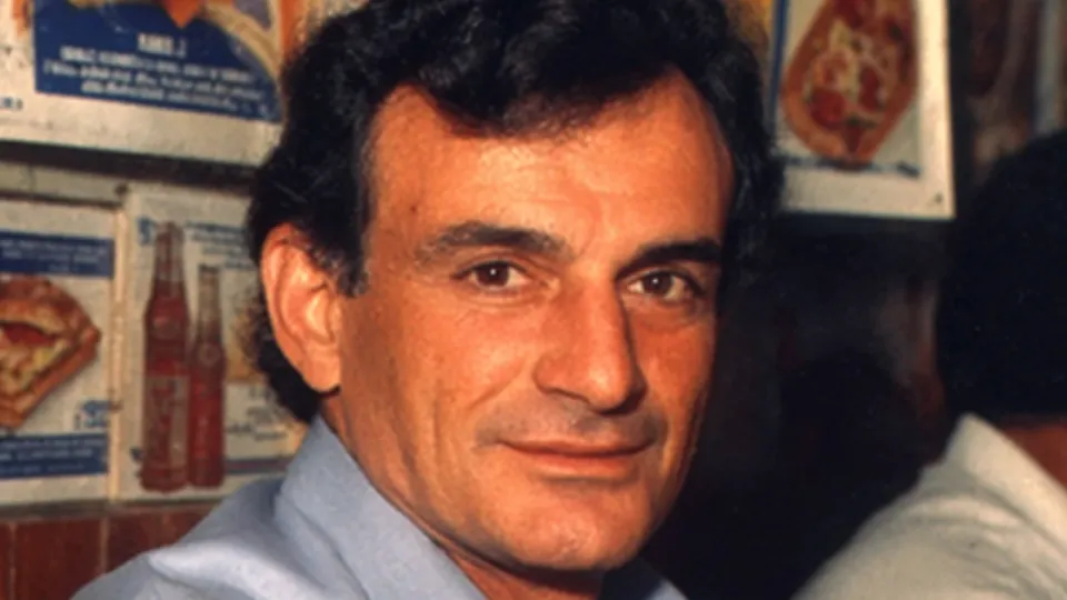 Fred DeLuca smiling in a light blue shirt inside an early sandwich shop