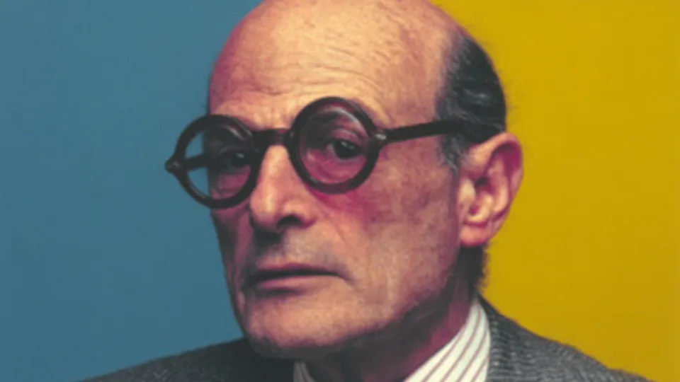 Portrait of an older man in round glasses and grey suit