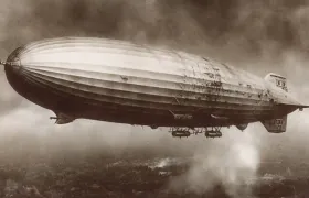 Sepia photograph of a rigid zeppelin airship flying above the clouds