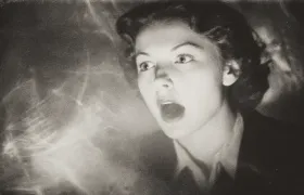 Terrified woman screaming amid ghostly streaks of light, staged in vintage photograph style